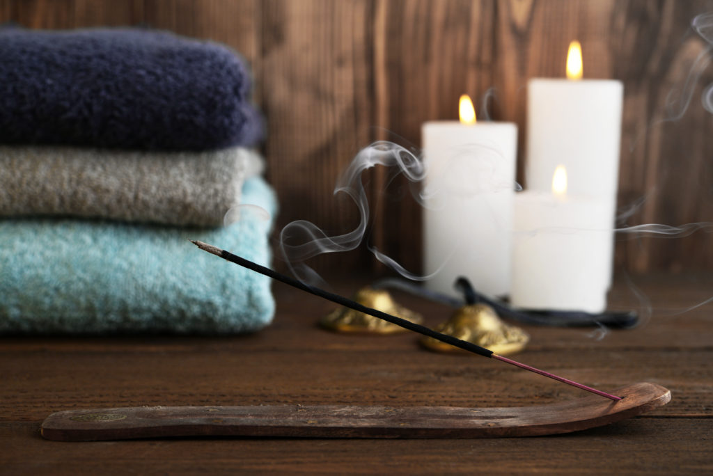 Bath ritual setting with incense and candles burning and towels.