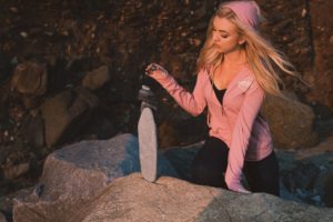 Blonde girl in pink sweatshirt practicing mindfulness, stacking rocks mindfully